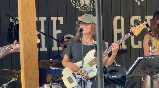 Charise Rogosky playing a white bass at an outdoor show in West Reading